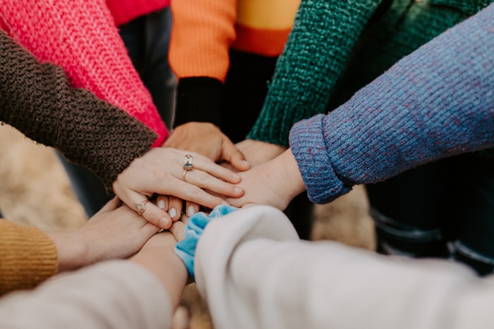 Group of people placing hands together, symbolizing teamwork and community support